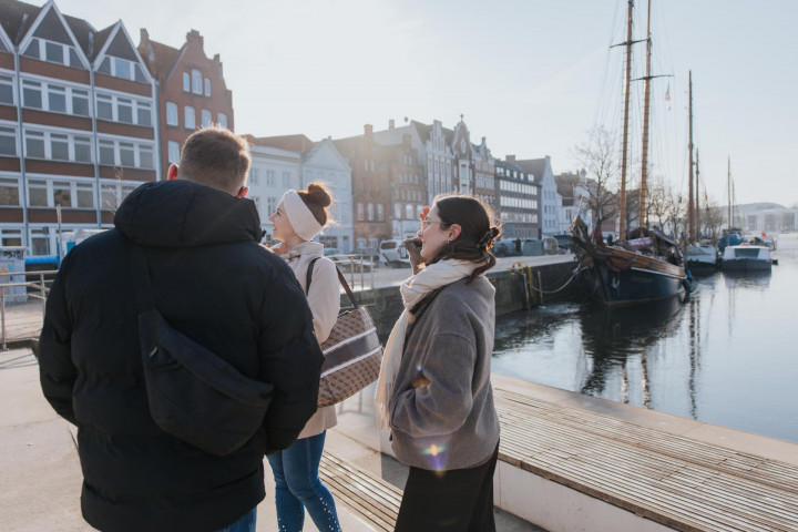 Drei Personen stehen in der Sonne am Drehbrückenplatz in Lübeck